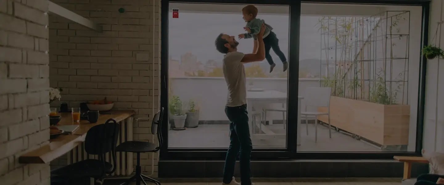 Padre che gioca col figlio in appartamento, mentre il sistema di allarme Sector Alarm garantisce sicurezza 24/7
