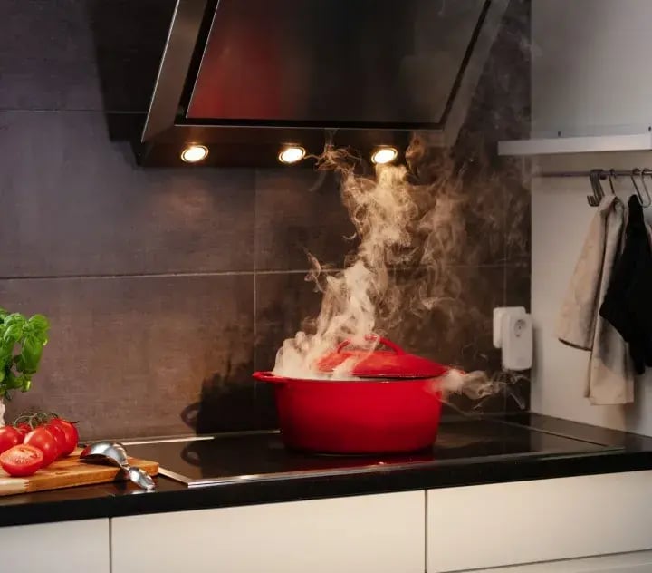 Fumo che esce da una pentola su un fornello acceso in cucina