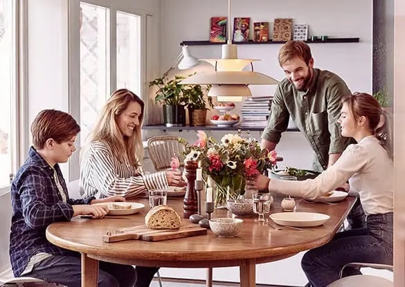 Famiglia riunita serena attorno a un tavolo da pranzo – immagine che comunica tranquillità e protezione grazie al sistema d’allarme Sector Alarm
